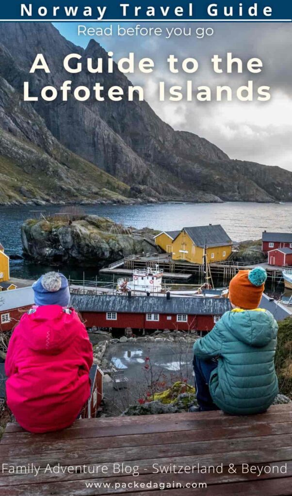 two children sitting on a bench in the lofoten village Nusfjord with mountains in the backjard