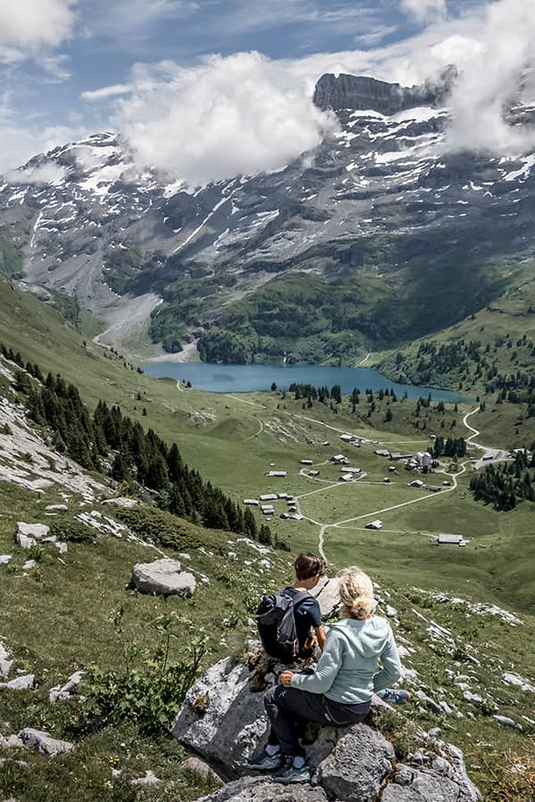 mother and son sitting on a rock looking down on to the Swiss alpine lake Engstlensee