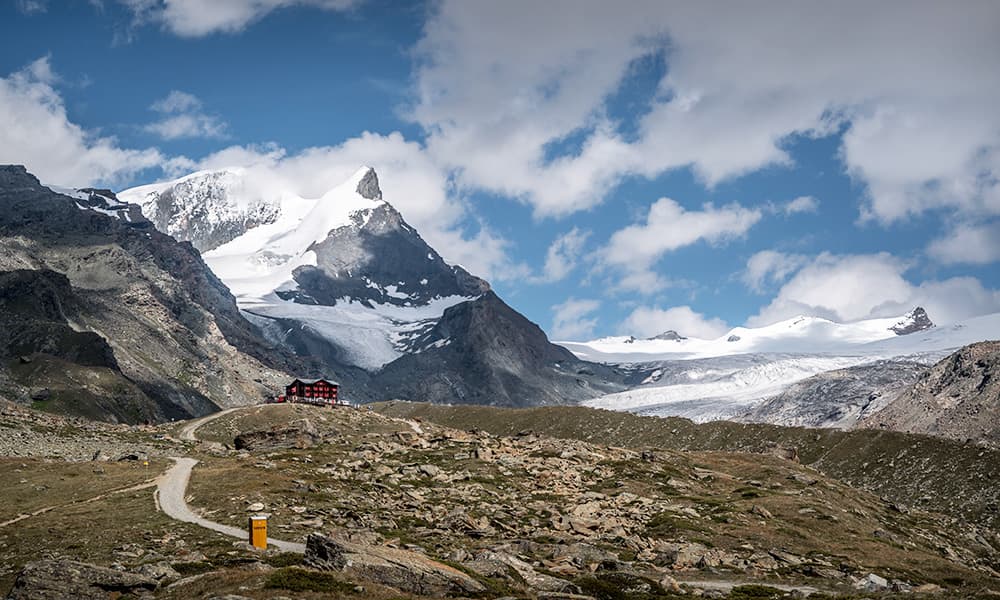 snow covered glacier and mountain with Fluhalp hut and blue sky 
