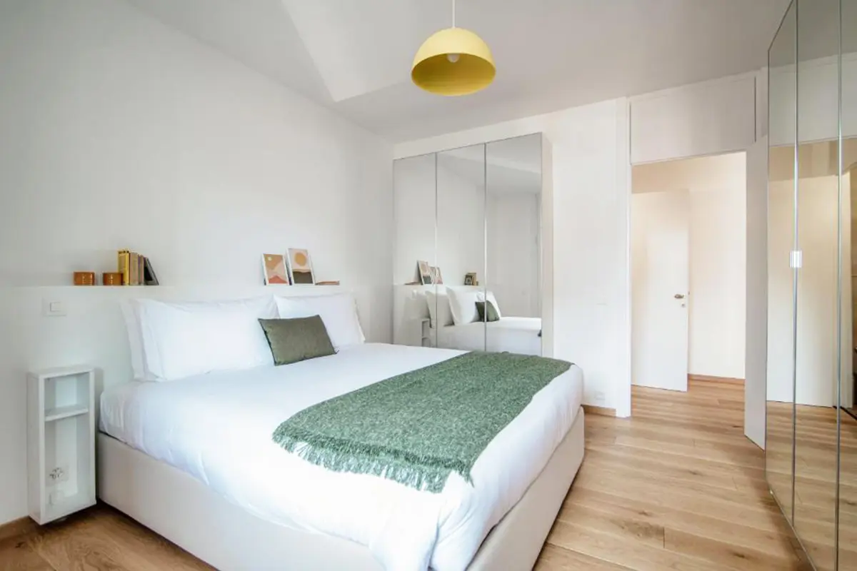 White clean bedroom in a Lugano Appartment with a green blanket on the bed