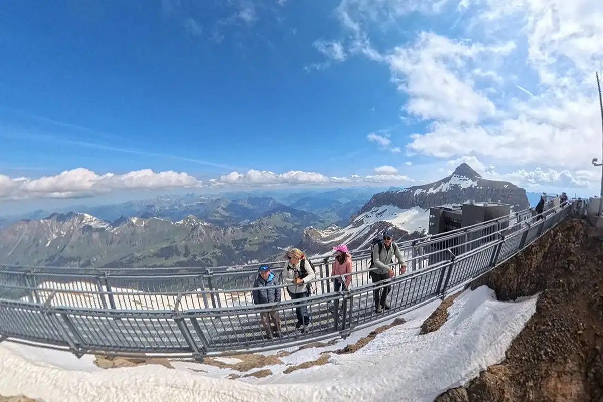 family standing high on a suspension bridge with epic view over Swiss alps
