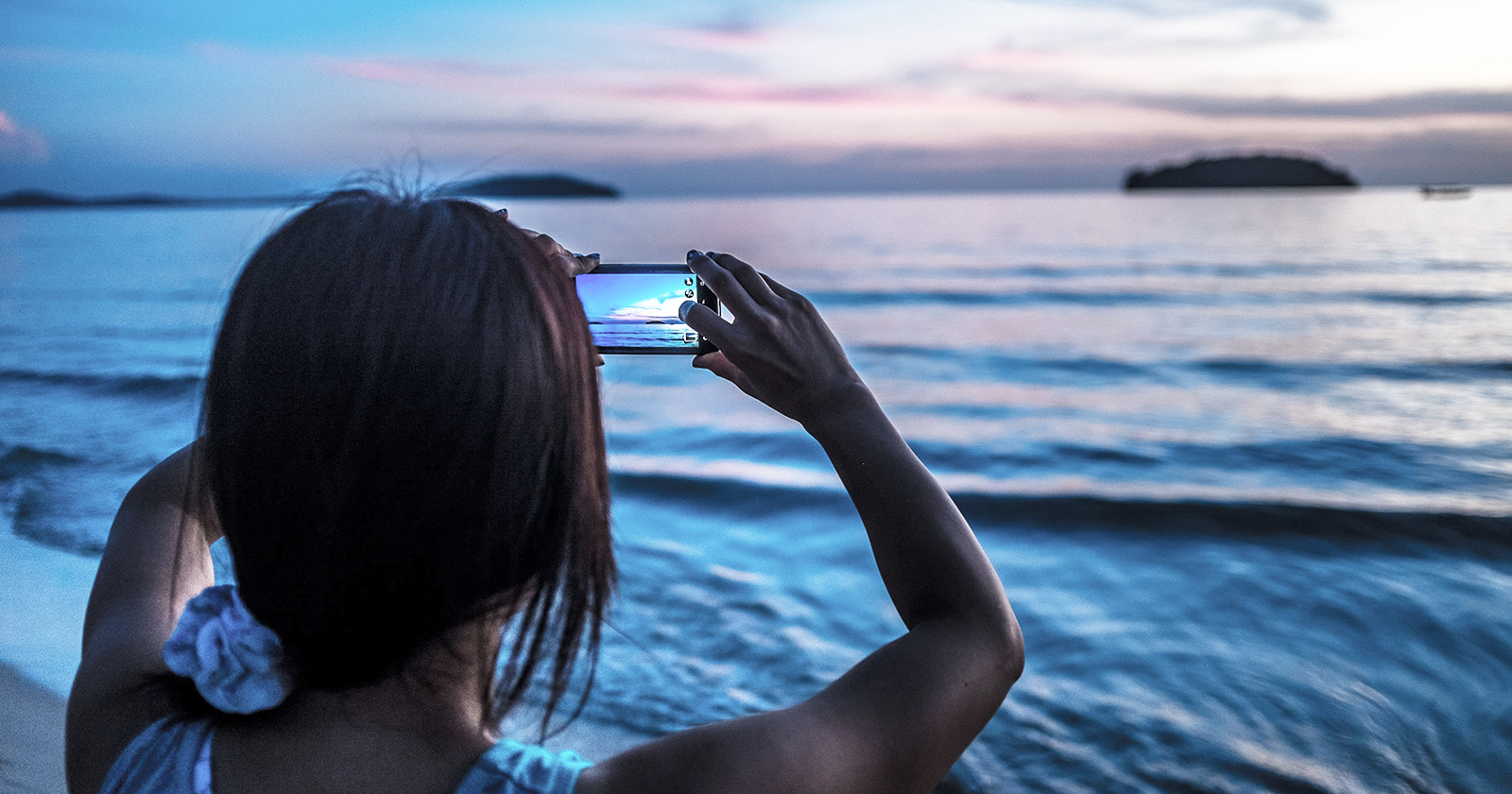 woman photographing the sunset with her iphone