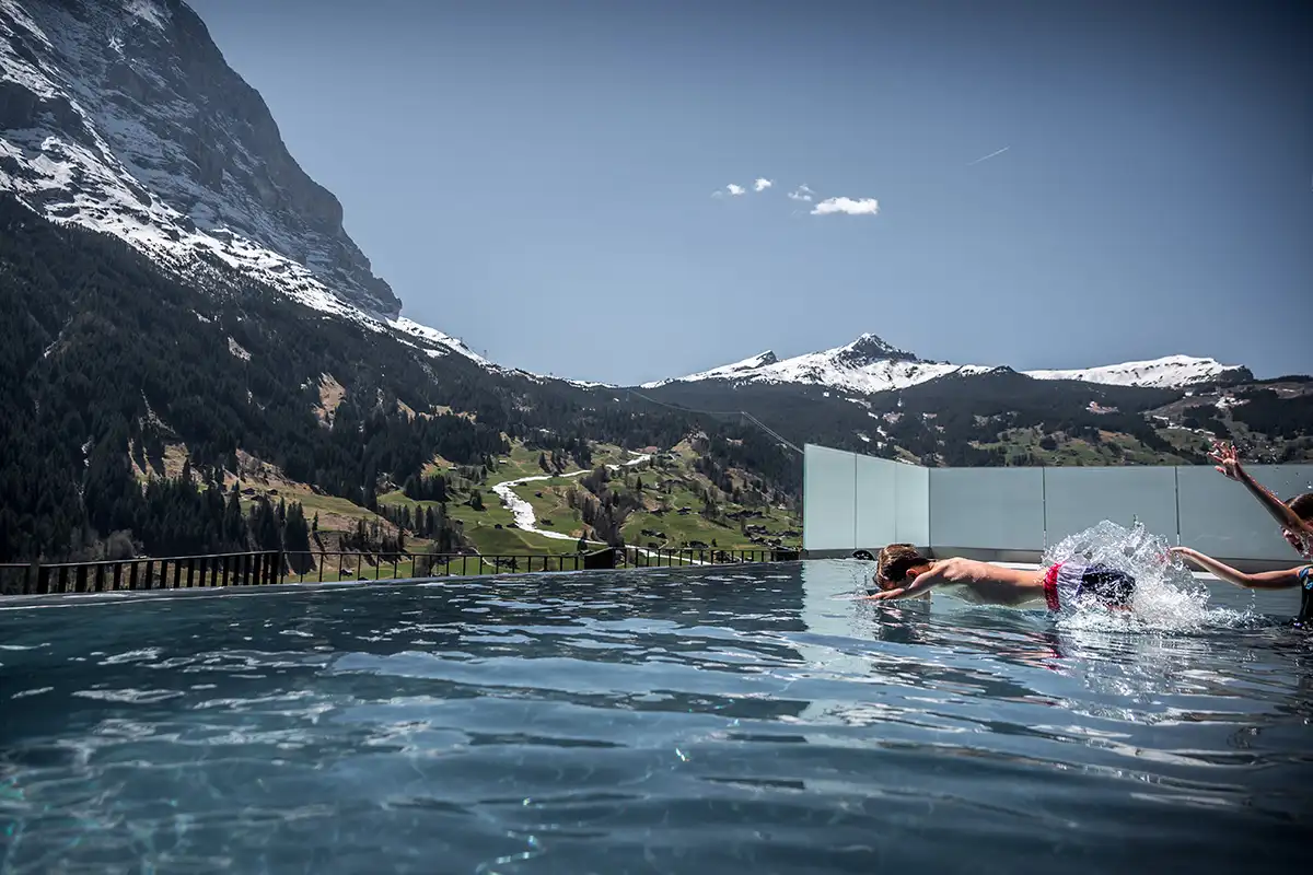 Children playing in the Hotel Spinne outdoor pool with the Eiger in the Background